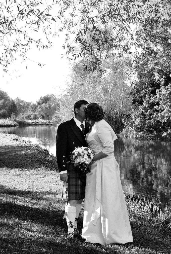 Bride and groom outdoors by river kissing | Michaela Howe Photography